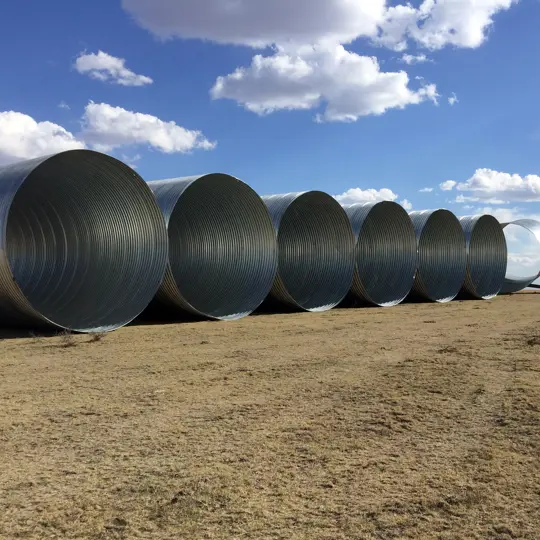 Large diameter corrugated metal drainage pipe staged for installation.